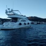 Un yate Sunseeker llamado "Silvia" amarrado en aguas tranquilas, con un paisaje costero al fondo.