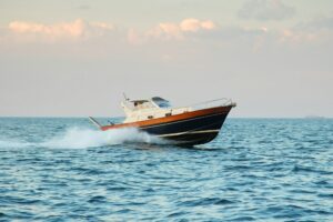 Un bote de motor con casco de madera y líneas negras navegando a alta velocidad por el mar, dejando una estela de agua detrás.