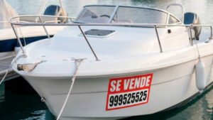 Barco de segunda mano con cartel de "Se vende" atracado en un puerto deportivo.